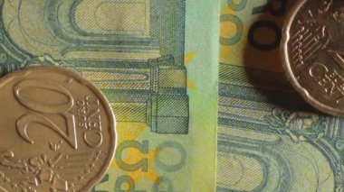 100 Euro 'luk banknotlara 20 Euro Cent madeni parası - Top View, Macro. Euro Para Birimi. Yeşil Kağıt Para. Yüz Euro 'luk banknot. İş, Finans, Para ve Tasarruf Konsepti - Yavaş Dönüşüm Sola