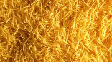 Saat Yönünde Yavaşça Dönen Pişmemiş Eriştelerin Arkaplanı - Üst Görünüm, Yakın Çekim. Kuru Vermicelli Dönüşü dokusu. Low Key Light ile Çiğ Makarna - Sağ Döndürme