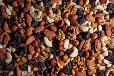 Karışık fındık, badem, ceviz, kaju, fıstık, fındık, kuru erik ve kuru üzüm. Farklı fındık karışımı. Çeşitli Fındık ve Kurutulmuş Meyvelerin Arkaplanı
