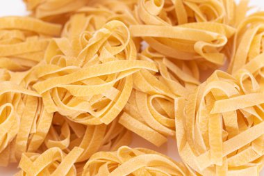 Klasik İtalyan Çiğ Yumurta Fettuccine Beyaz Masa 'da. Kuru, bükülmemiş, pişmemiş makarna. İtalyan Kültür ve Mutfağı. Çiğ Altın Makarna Deseni