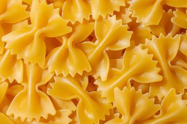 Pişmemiş Farfalle Makarnası: Gurme Aşçılık İçin Canlı ve Dokulu Bir Arkaplan Oluşturan Papyonlu Makarna Mutfağı. Kuru makarna. Raw Macaroni - Top View, Düz Yat