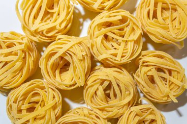 Uncooked Egg-Based Fettuccine Pasta: A Culinary Canvas of Ribbon-Shaped Macaroni, Creating a Lively and Textured Background for Gourmet Cooking. Dry Pasta. Raw Macaroni - Top View, Flat Lay clipart