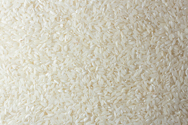 Dry Uncooked White Rice Background - Top View, Flat Lay. Scattered Raw Long Grain Rice. Asian Cuisine and Culture. Healthy Eating Ingredients. Diet Food