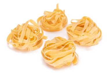 Dört klasik İtalyan Çiğ Yumurta Fettuccine, beyaz arka planda izole edilmiş. Kuru, bükülmemiş, pişmemiş makarna. İtalyan Kültür ve Mutfağı. Çiğ Altın Makarna Deseni - İzolasyon