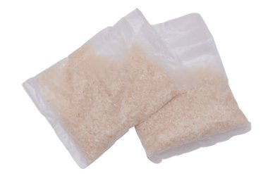 Beyaz arka planda izole edilmiş uzun pirinç taneli plastik torbalar. Kuru Pirinç içeren küçük şeffaf paketler - izolasyon