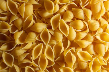 Pişmemiş Conchiglie Pasta: Konchiglie Macaroni 'nin Mutfak Tuvali, Gurme Yemekleri İçin Canlı ve Dokulu Bir Arkaplan Oluşturuyor. Kuru makarna. Raw Macaroni - Top View, Düz Yat