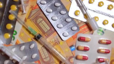 Enflasyon. Pahalı bir ilaç. Yüksek Sağlık Hizmetleri Maliyeti. Global İlaç Endüstrisi ve Tıbbi Ürünler. Elli Avro Banknotunda Farklı İlaç ve Şırıngalar - Üst Görünüm, Dönüşüm Hakkı