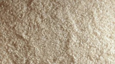 Kuru pişmemiş beyaz pirinç arka planı sola dönüyor - Üst Manzara, alçak anahtar ışığı. Çiğ Uzun Taneli Pirinç. Asya mutfağı ve kültürü. Sağlıklı beslenme malzemeleri. Diyet Yemekler