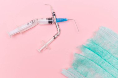 Aşı Karşıtı Hareket ve Maske Karşıtı Konsept - Kırık Tıbbi Şırınga ve Pembe Arkaplanda Yeşil Yırtık Tıbbi Maske. Salgın ve Kilitlenme Sonu - Üst Görünüm, Düz Yat