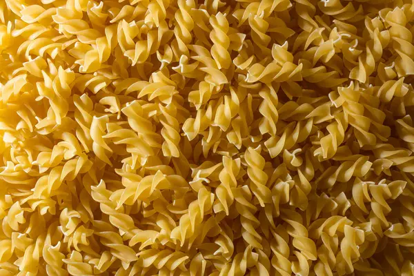 Pişmemiş Fusilli Makarna: Bir Spiral Makarna Mutfağı, Gurme Yemekleri İçin Canlı ve Dokulu Bir Arkaplan Oluşturma. Kuru makarna. Raw Macaroni - Top View, Düz Yat