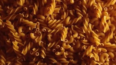 Pişmemiş Fusilli ve Chifferi Rigati Pasta Üst Manzara, Alçak Anahtar Işığı. Şişman ve Sağlıksız Yemek. Klasik Kuru Makarna, Dönen Arka plan. Raw Different Macaroni Makarna Dokusunu Sola Döndür