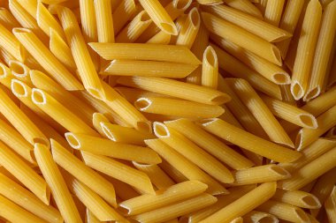 Pişmemiş Penne Rigate Makarnası: Gurme Aşçılık İçin Canlı ve Dokulu Bir Arkaplan Oluşturan Penne Makarna Mutfağı. Kuru makarna. Raw Macaroni - Top View, Düz Yat