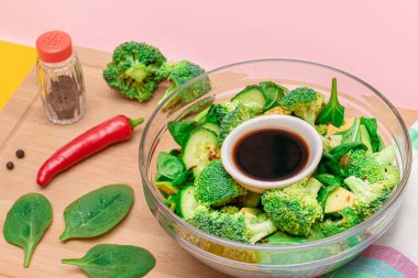 Taze Yeşil Avokado Salatası, Brokoli, Ispanak ve Salatalık ve Soya Sosu ve Tahta Kesme Kurulunda Kırmızı Acı Biber. Vejetaryen salatası. Vejetaryen Kültürü. Çiğ yemek. Sağlıklı beslenme ve sebze diyeti