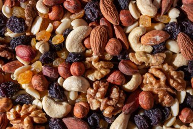 Karışık fındık, badem, ceviz, kaju, fıstık, fındık, kuru erik ve kuru üzüm. Farklı fındık karışımı. Çeşitli Fındık ve Kurutulmuş Meyvelerin Arkaplanı