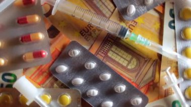 Enflasyon. Pahalı bir ilaç. Yüksek Sağlık Hizmetleri Maliyeti. Global İlaç Endüstrisi ve Tıbbi Ürünler. Elli Avro Banknotunda Farklı İlaç ve Şırıngalar - Üst Görünüm, Dönüşüm Hakkı