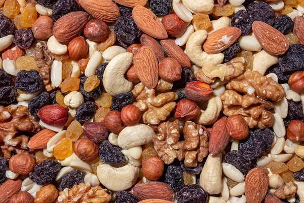 Karışık fındık, badem, ceviz, kaju, fıstık, fındık, kuru erik ve kuru üzüm. Farklı fındık karışımı. Çeşitli Fındık ve Kurutulmuş Meyvelerin Arkaplanı