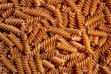 Pişmemiş Whole Grain Fusilli Makarna: Gurme Aşçılık İçin Canlı ve Dokulu Bir Arkaplan Oluşturan Tam Buğday Büfesi. Tam Tahıllı Kurutulmuş Makarna. Tam buğday hamurlu makarna.