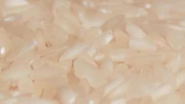 Dry Uncooked White Rice Rotating - Macro. Scattered Raw Long Grain Rice - Close-Up. Asian Cuisine and Culture. Healthy Eating Ingredients. Diet Food