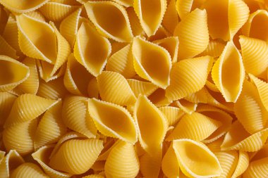 Pişmemiş Conchiglie Pasta: Konchiglie Macaroni 'nin Mutfak Tuvali, Gurme Yemekleri İçin Canlı ve Dokulu Bir Arkaplan Oluşturuyor. Kuru makarna. Raw Macaroni - Top View, Düz Yat