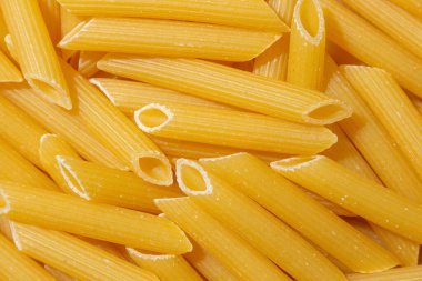 Pişmemiş Penne Rigate Makarnası: Gurme Aşçılık İçin Canlı ve Dokulu Bir Arkaplan Oluşturan Penne Makarna Mutfağı. Kuru makarna. Raw Macaroni - Top View, Düz Yat