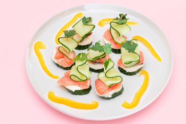 Taze somonlu kanepeler, salatalık ve krem peynirli beyaz tabak. Kolay Kahvaltı 'da. Diyet yemek. Hızlı ve sağlıklı sandviçler. Lezzetli Doldurulmuş Sağlıklı Atıştırmalıklar