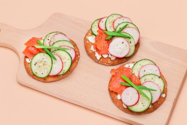 Taze somon, salatalık, turp, süzme peynir ve taze soğanlı çıtır krakerli sandviç. Kolay Kahvaltı 'da. Hızlı ve sağlıklı sandviçler. Lezzetli dolgulu kızarmış ekmek. Sağlıklı Beslenme Atıştırması