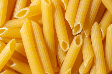 Pişmemiş Penne Rigate Makarnası: Gurme Aşçılık İçin Canlı ve Dokulu Bir Arkaplan Oluşturan Penne Makarna Mutfağı. Kuru makarna. Raw Macaroni - Top View, Düz Yat