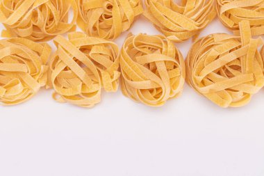 Klasik İtalyan Raw Egg Fettuccine, Beyaz Arkaplanda Kopya Spase. Kuru, bükülmemiş, pişmemiş makarna. İtalyan Kültür ve Mutfağı. Çiğ Altın Makarna Deseni