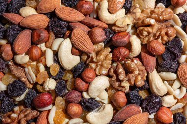 Karışık fındık, badem, ceviz, kaju, fıstık, fındık, kuru erik ve kuru üzüm. Farklı fındık karışımı. Çeşitli Fındık ve Kurutulmuş Meyvelerin Arkaplanı