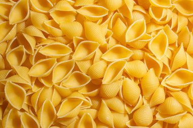 Pişmemiş Conchiglie Pasta: Konchiglie Macaroni 'nin Mutfak Tuvali, Gurme Yemekleri İçin Canlı ve Dokulu Bir Arkaplan Oluşturuyor. Kuru makarna. Raw Macaroni - Top View, Düz Yat