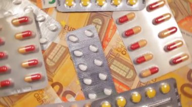 Enflasyon. Pahalı bir ilaç. Yüksek Sağlık Hizmetleri Maliyeti. Global İlaç Endüstrisi ve Tıbbi Ürünler. 50 Euro 'luk banknotların üzerindeki haplar - Üst Manzara, Dönüşüm Solu
