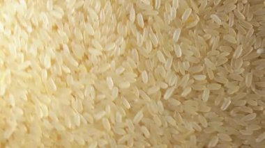 Kuru, haşlanmamış pirinç arka planı saat yönünde dönüyor - Üst görünüm. Çiğ Uzun Taneli Pirinç. Asya mutfağı ve kültürü. Sağlıklı beslenme malzemeleri. Diyet yemek. Açısal Döndürme Sağa