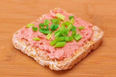 Balık kremalı Rice Cake Sandviçi ve bambu kesme tahtasında taze soğan. Kolay Kahvaltı 'da. Diyet yemek. Hızlı ve sağlıklı sandviçler. Lezzetli dolgulu kızarmış ekmek. Sağlıklı Beslenme Atıştırması