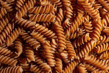 Pişmemiş Whole Grain Fusilli Makarna: Gurme Aşçılık İçin Canlı ve Dokulu Bir Arkaplan Oluşturan Tam Buğday Büfesi. Tam Tahıllı Kurutulmuş Makarna. Tam buğday hamurlu makarna.