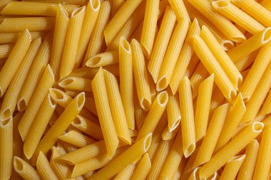 Pişmemiş Penne Rigate Makarnası: Gurme Aşçılık İçin Canlı ve Dokulu Bir Arkaplan Oluşturan Penne Makarna Mutfağı. Kuru makarna. Raw Macaroni - Top View, Düz Yat