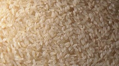 Kuru, haşlanmamış pirinçli arka plan sola dönüyor - Üst Manzara, alçak anahtar ışığı. Çiğ Uzun Taneli Pirinç. Asya mutfağı ve kültürü. Sağlıklı beslenme malzemeleri. Diyet Yemekler