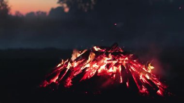 Büyük Kamp Ateşi, Sabah Erkenden veya Akşam Mavi Gök 'e Karşı Yanıyor. Ateşe odun. Uçan Kıvılcım. Seyahat ve Turizm Konsepti. Yaz 'da Devasa Şenlik Ateşi' nden Kalanlar - Statik Çekim, Zaman Aşımı