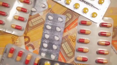 Enflasyon. Pahalı bir ilaç. Yüksek Sağlık Hizmetleri Maliyeti. Global İlaç Endüstrisi ve Tıbbi Ürünler. 50 Euro 'luk banknotların üzerindeki haplar - Üst Görünüm, Yavaş Rotasyon Sağa