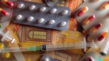 Enflasyon. Pahalı bir ilaç. Yüksek Sağlık Hizmetleri Maliyeti. Global İlaç Endüstrisi ve Tıbbi Ürünler. Elli Avro Banknotunda Farklı İlaç ve Şırıngalar - Üst Görünüm, Dönüşüm Solu