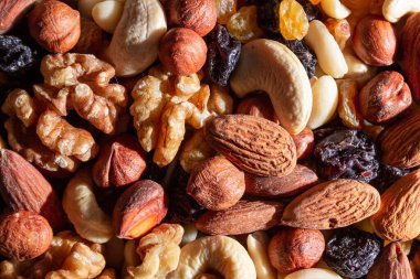 Karışık fındık, badem, ceviz, kaju, fıstık, fındık, kuru erik ve kuru üzüm. Farklı fındık karışımı. Çeşitli Fındık ve Kurutulmuş Meyvelerin Arkaplanı