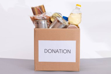 Bağış Kutusu Bedava Yemek. İçinde konserve yiyecek, mısır gevreği ve market olan bir karton kutu. Yemek rezervleri. Kriz anında acil durum gıda deposu. Ücretsiz Sosyal Yardım, Lütuf ve Bakım. Stratejik Gıda Malzemeleri