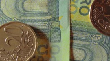 100 Euro 'luk banknotlara 20 Euro Cent madeni parası - Top View, Macro. Euro Para Birimi. Yeşil Kağıt Para. Yüz Euro 'luk banknot. İş, Finans, Para ve Tasarruf Konsepti - Yavaş Dönüşüm Sola