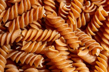 Pişmemiş Whole Grain Fusilli Makarna: Gurme Aşçılık İçin Canlı ve Dokulu Bir Arkaplan Oluşturan Tam Buğday Büfesi. Tam Tahıllı Kurutulmuş Makarna. Tam buğday hamurlu makarna.