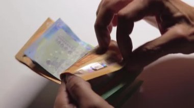 Elde Para Saymak. Avrupa Birliği Parası. Beyaz Adam Beyaz Masa 'da Farklı Euro Banknotları Sayıyor - Yavaş Hareket. Renkli Kağıt Para. Avro Elde. Gelir, Tasarruf ve Harcama Konsepti