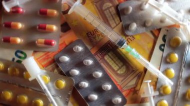 Enflasyon. Pahalı bir ilaç. Yüksek Sağlık Hizmetleri Maliyeti. Global İlaç Endüstrisi ve Tıbbi Ürünler. Elli Avro Banknotunda Farklı İlaç ve Şırıngalar - Üst Görünüm, Dönüşüm Solu