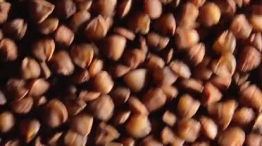 Kuru pişmemiş kahverengi karabuğday Groats, Saat Yönünün Tersine Dönen Üst Görünüm, Yakın Çekim, Makro, Alçak Anahtar Işığı. Çiğ Büyük Karabuğday Taneleri. Rus, Ukrayna ve Beyaz Rusya Kültürü. Sola Döndür