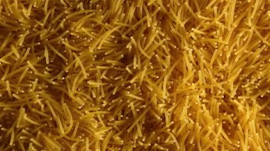 Saat Yönünün Tersine Yavaşça Dönen Pişmemiş Eriştelerin Arkaplanı - Üst Görünüm, Yakın Çekim. Kuru Vermicelli Dönüşü dokusu. Low Key Light ile Çiğ Makarna - Sol Çevirme