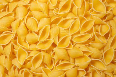 Pişmemiş Conchiglie Pasta: Konchiglie Macaroni 'nin Mutfak Tuvali, Gurme Yemekleri İçin Canlı ve Dokulu Bir Arkaplan Oluşturuyor. Kuru makarna. Raw Macaroni - Top View, Düz Yat