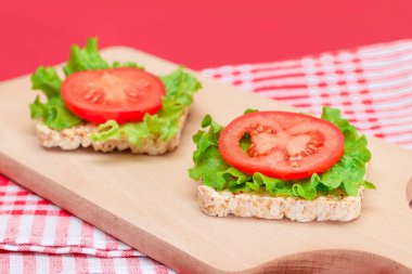 Domatesli pirinçli sandviç ve tahta kesim tahtasında marul. Kolay Kahvaltı 'da. Diyet yemek. Hızlı ve sağlıklı sandviçler. Lezzetli dolgulu kızarmış ekmek. Sağlıklı Beslenme Atıştırması