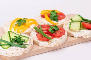 Tahta kesim tahtasında taze domatesli farklı vejetaryen pirinç keki sandviçleri, sarı paprika ve yeşillikler. Vejetaryen Diyet Yemekleri. Hızlı ve sağlıklı sandviçler. Taze dolgulu çıtır ekmek.